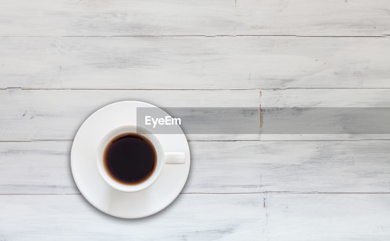 COFFEE CUP ON TABLE AGAINST WOODEN WALL