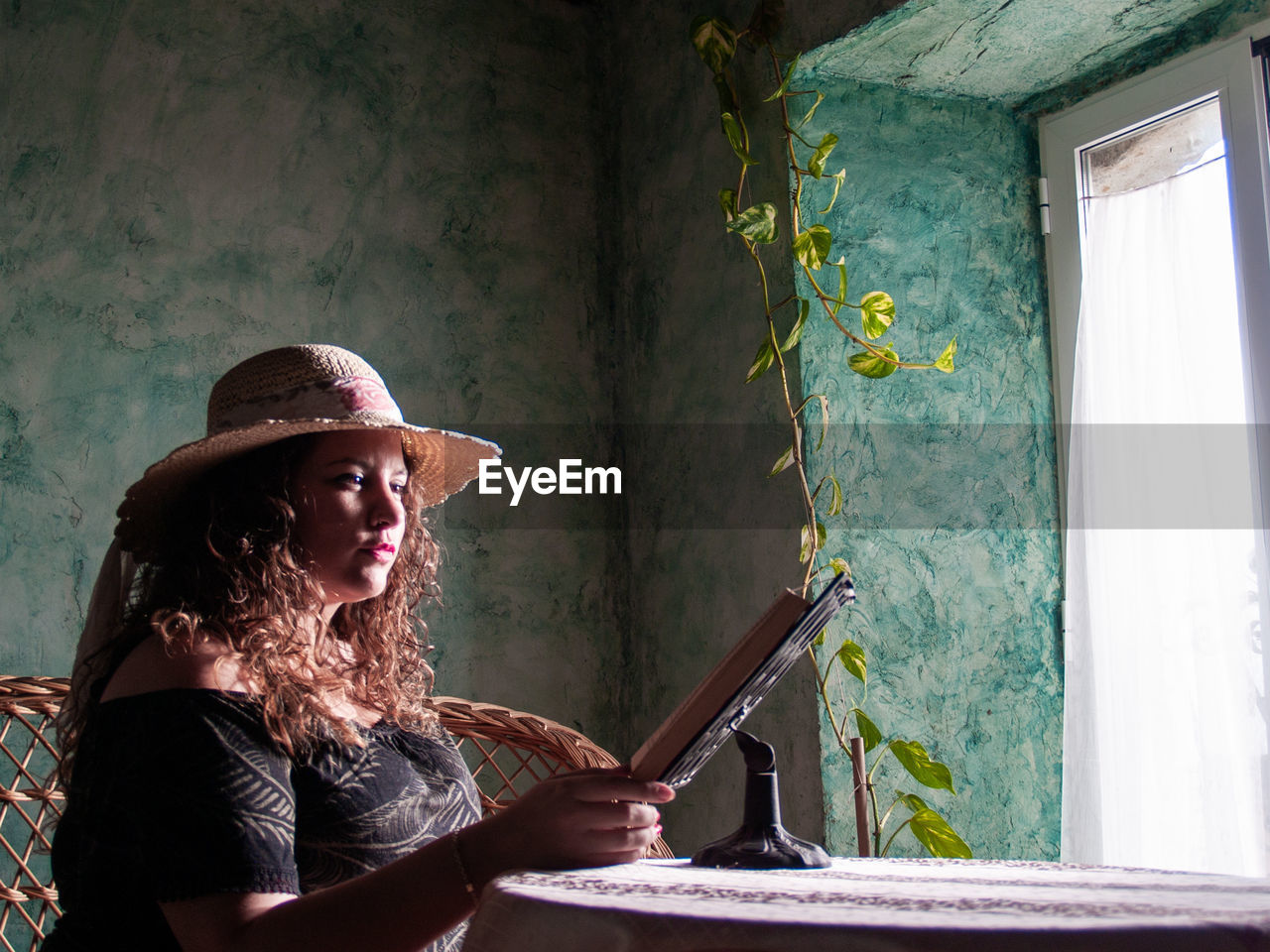 Woman reading book on table at home