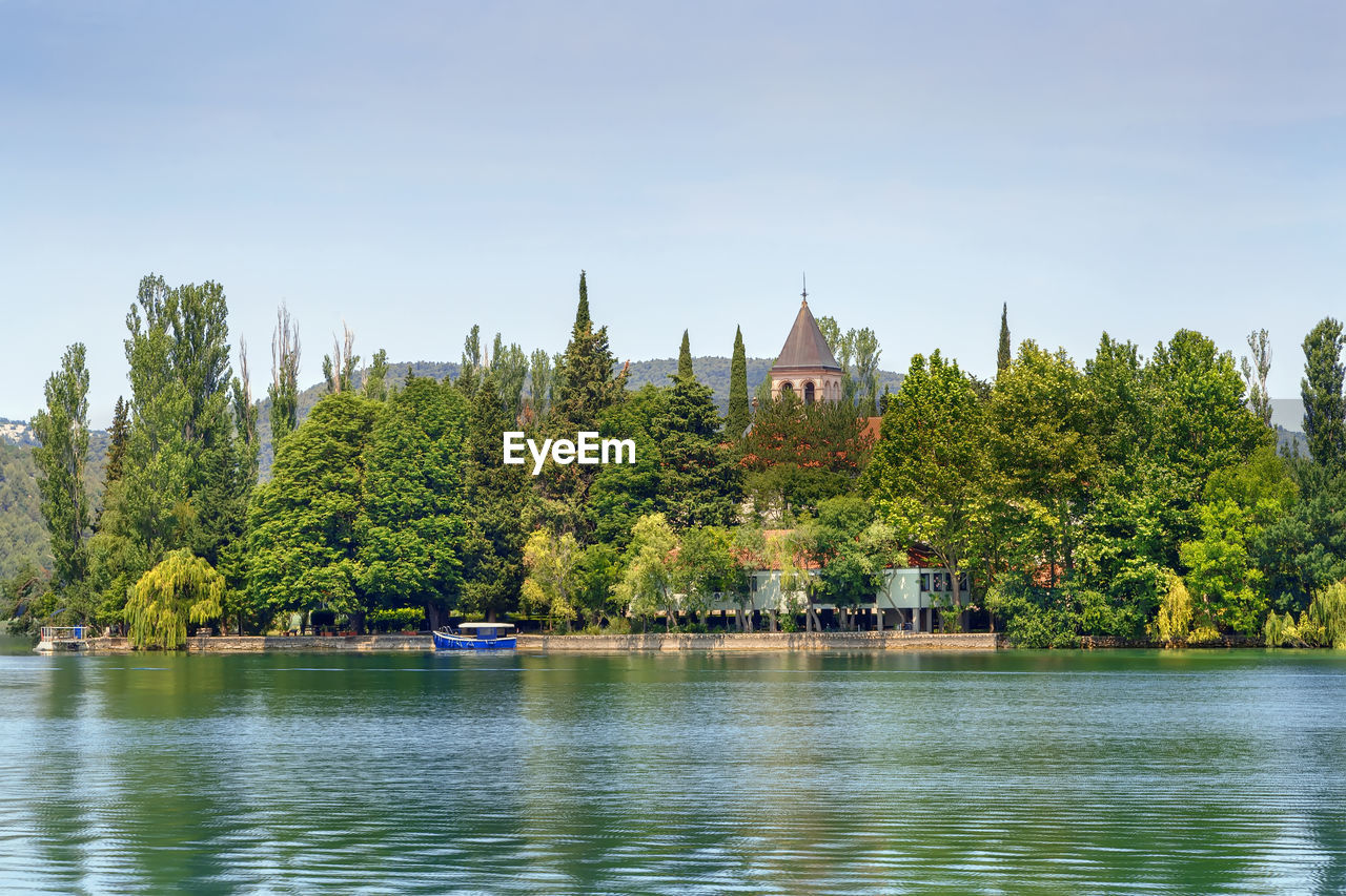 VIEW OF TREES BY LAKE AGAINST SKY