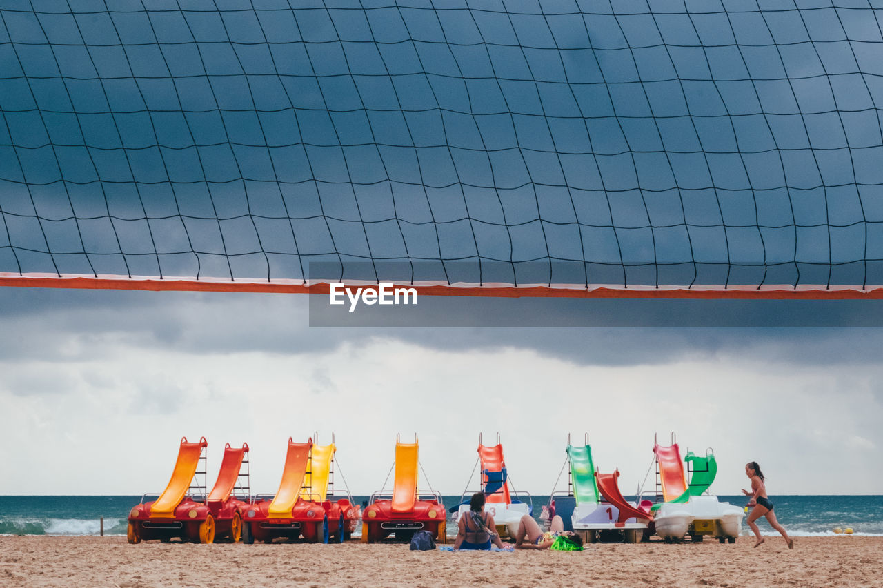 Deck chairs on beach against sky