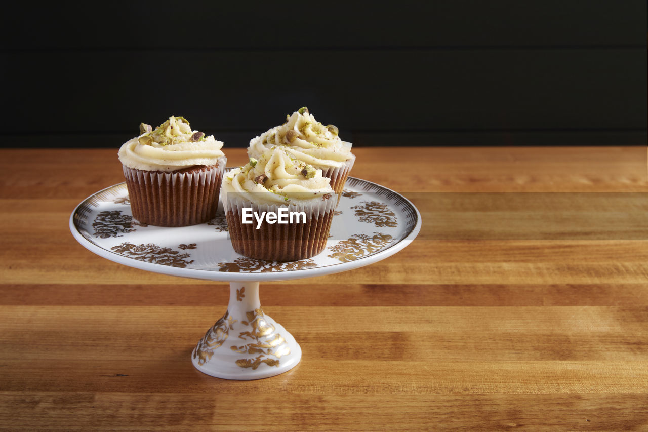 CLOSE-UP OF CUPCAKES AGAINST TABLE