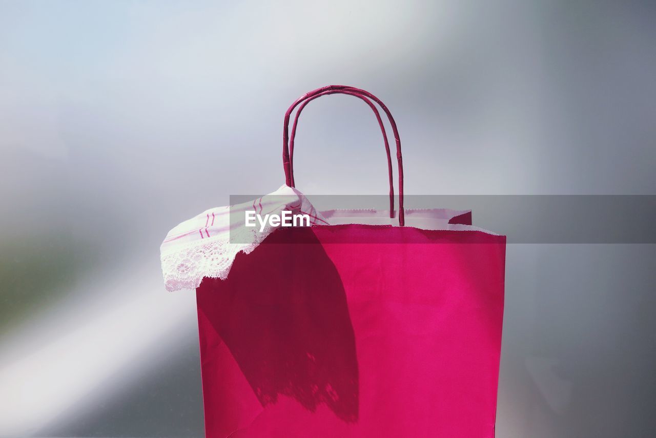 Close-up view of pink shopping bag against gray background