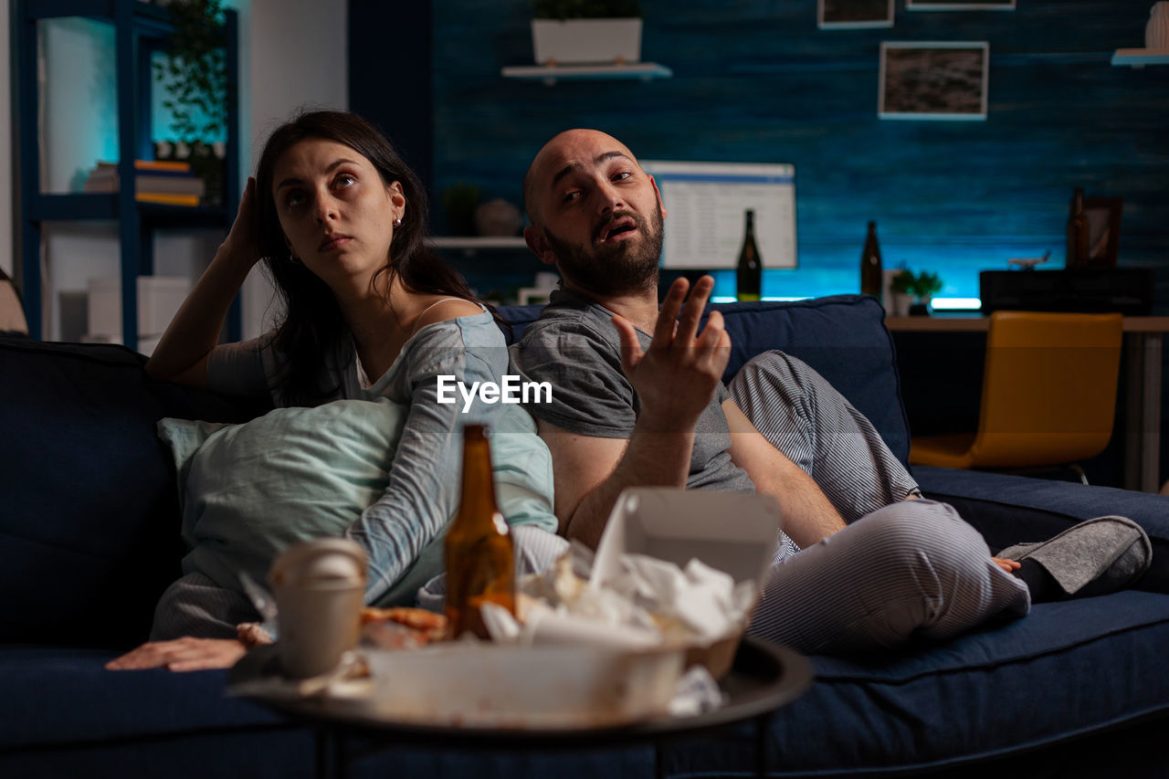 portrait of smiling friends sitting on table at home