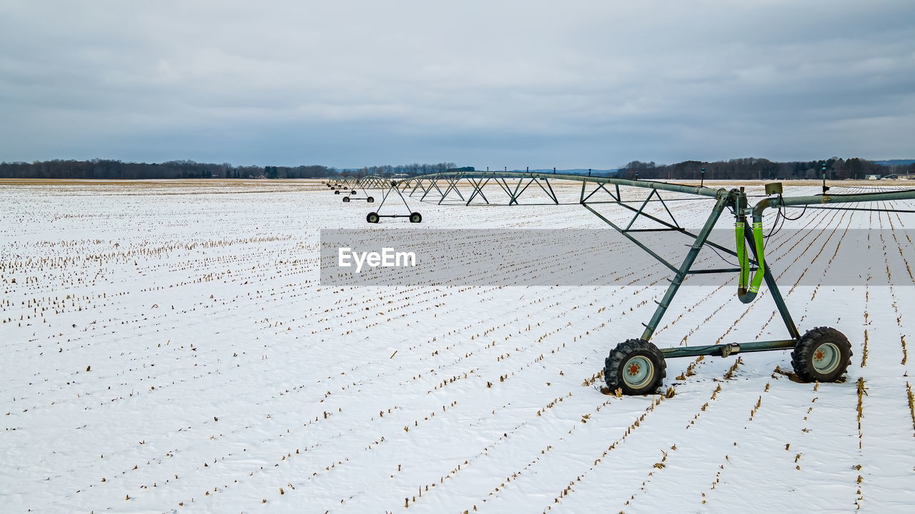 Snow covers the landscape with agricultural equipment left out