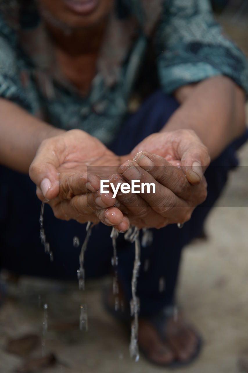 Low section of man holding water in cupped hands