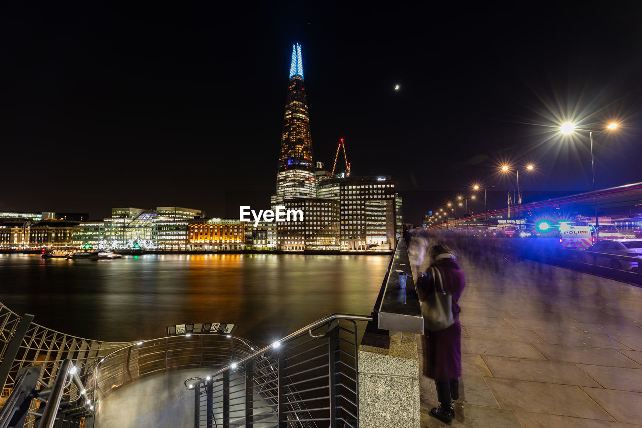 River against illuminated buildings in city at night