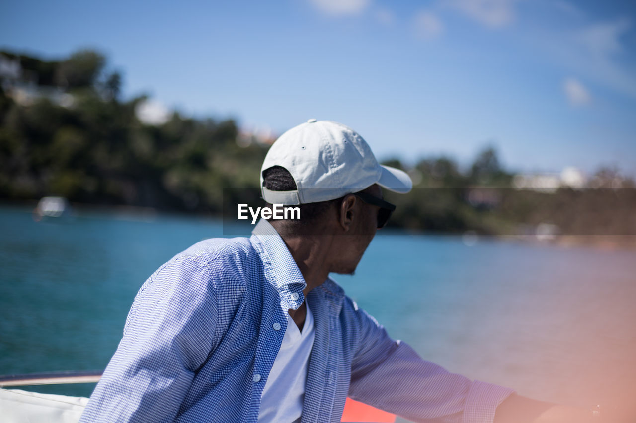 Man wearing hat against sea against sky