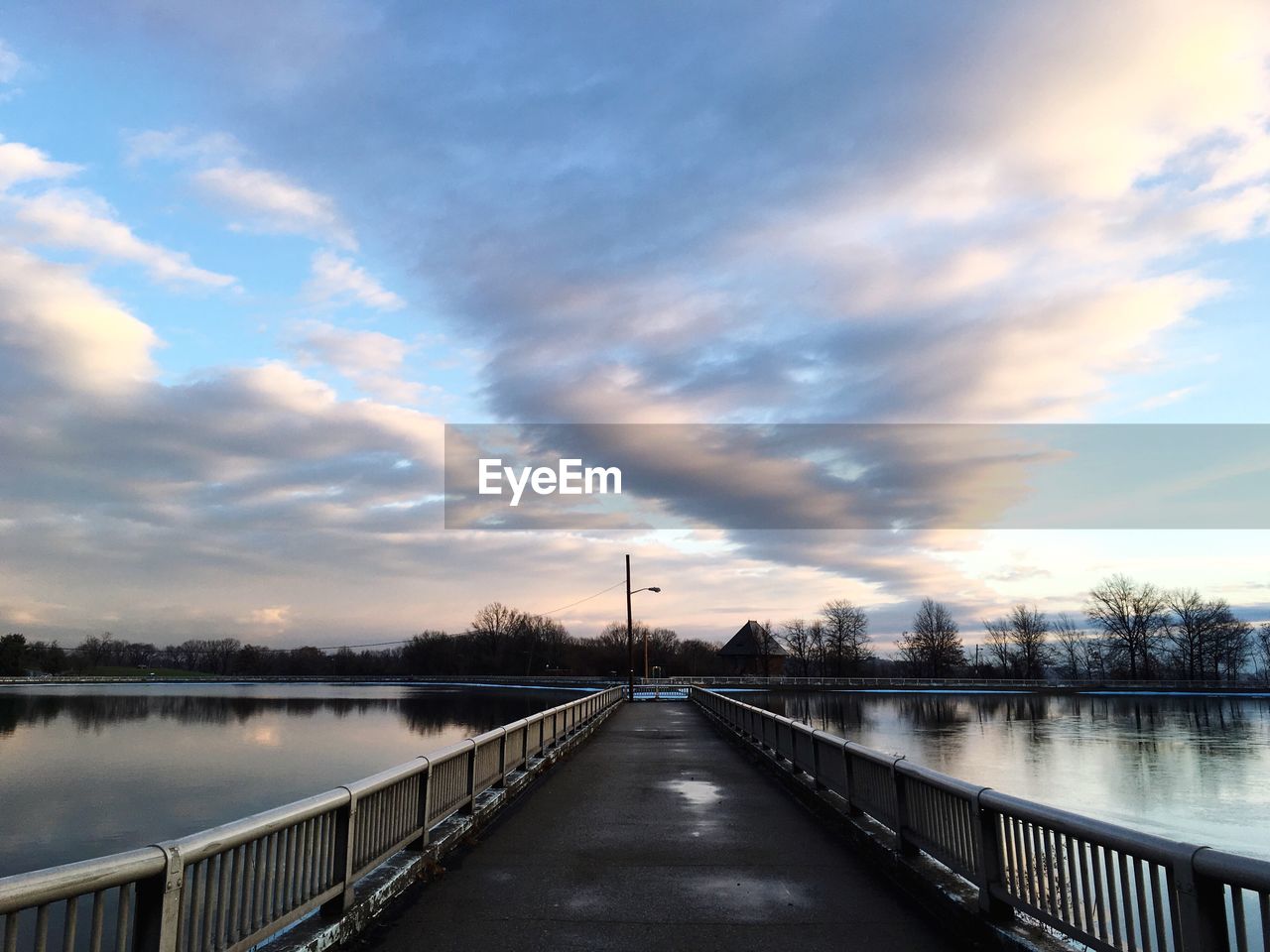 Bridge over river against cloudy sky