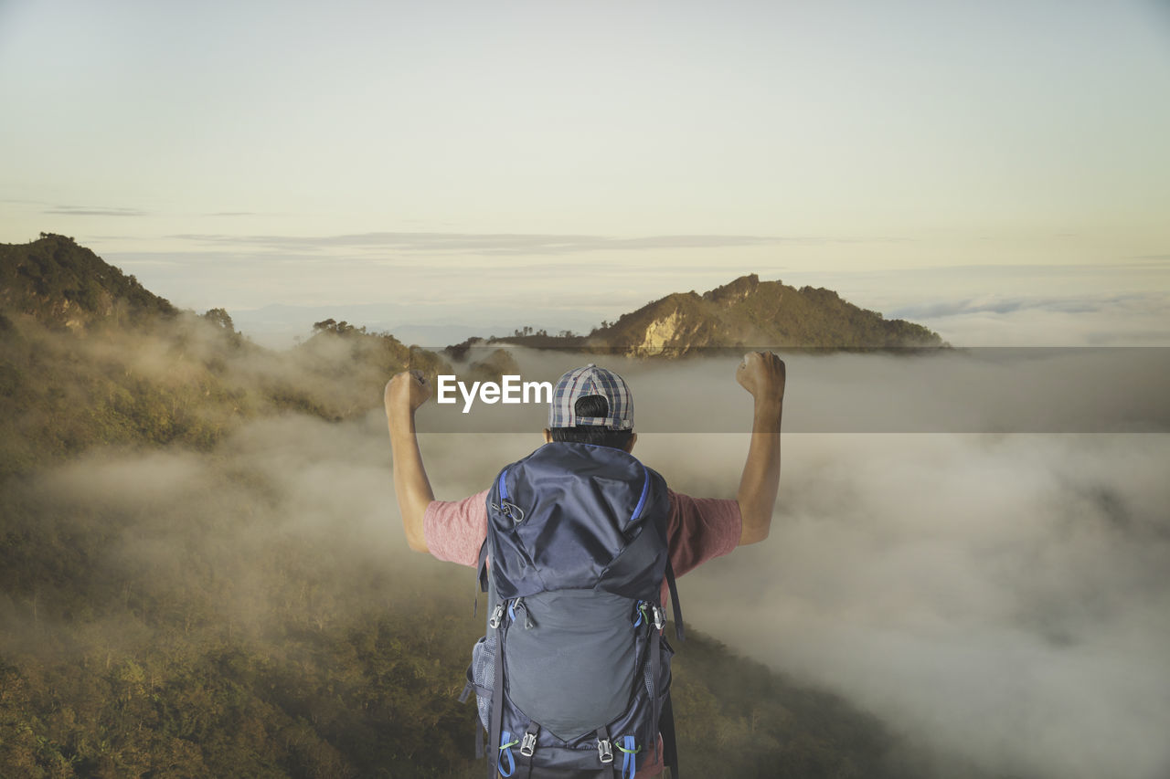 Young man with backpack enjoying sunset on peak mountain. tourist traveler.