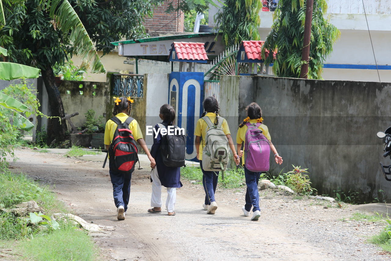 REAR VIEW OF FRIENDS WALKING ON FOOTPATH