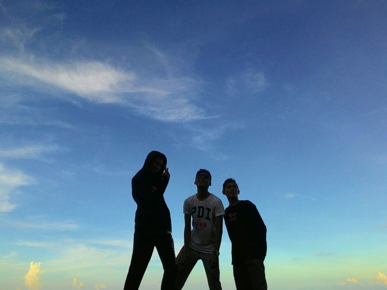 LOW ANGLE VIEW OF SILHOUETTE FRIENDS STANDING AGAINST CLOUDY SKY