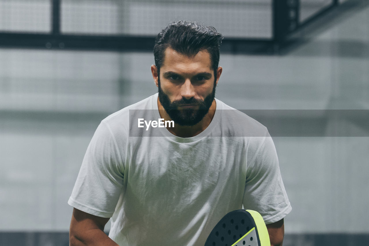 Man playing paddle tennis, racket in hand concentrated look. young sporty boy ready for the match.