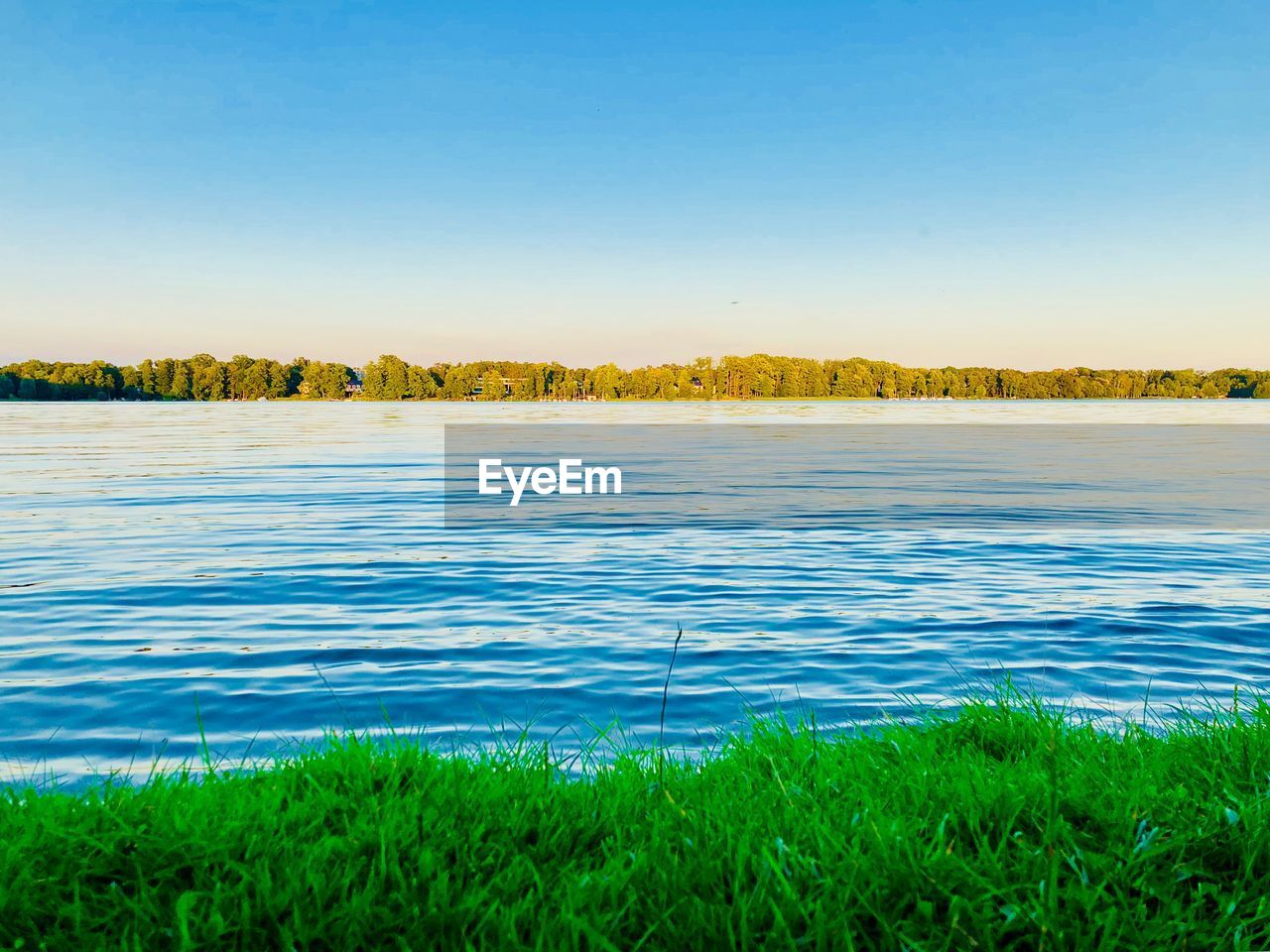 Scenic view of lake against clear blue sky