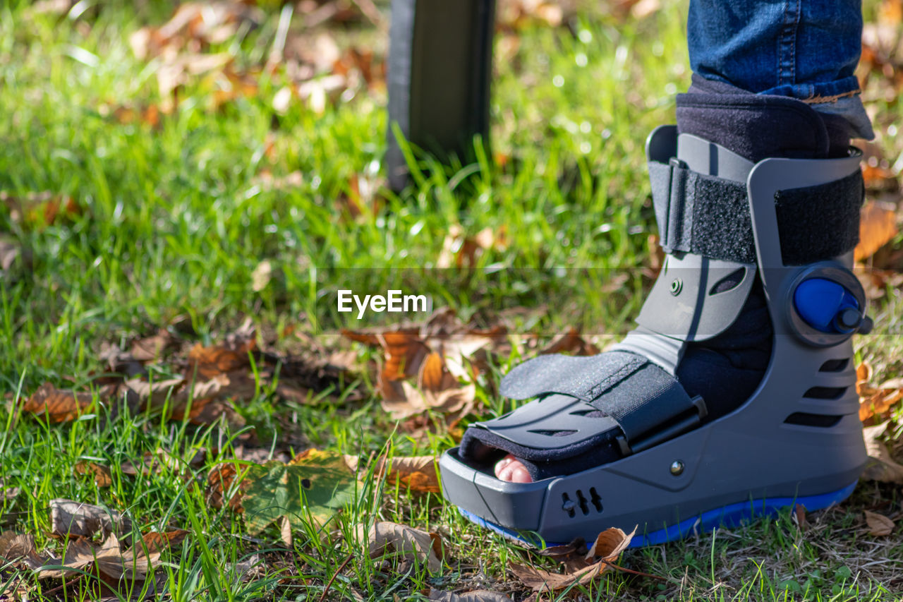 lawn, footwear, grass, plant, green, shoe, nature, low section, day, one person, yellow, outdoors, human leg, land, field, focus on foreground, technology, limb, childhood, human limb, lifestyles, leisure activity, boot, close-up, spring, adult, growth