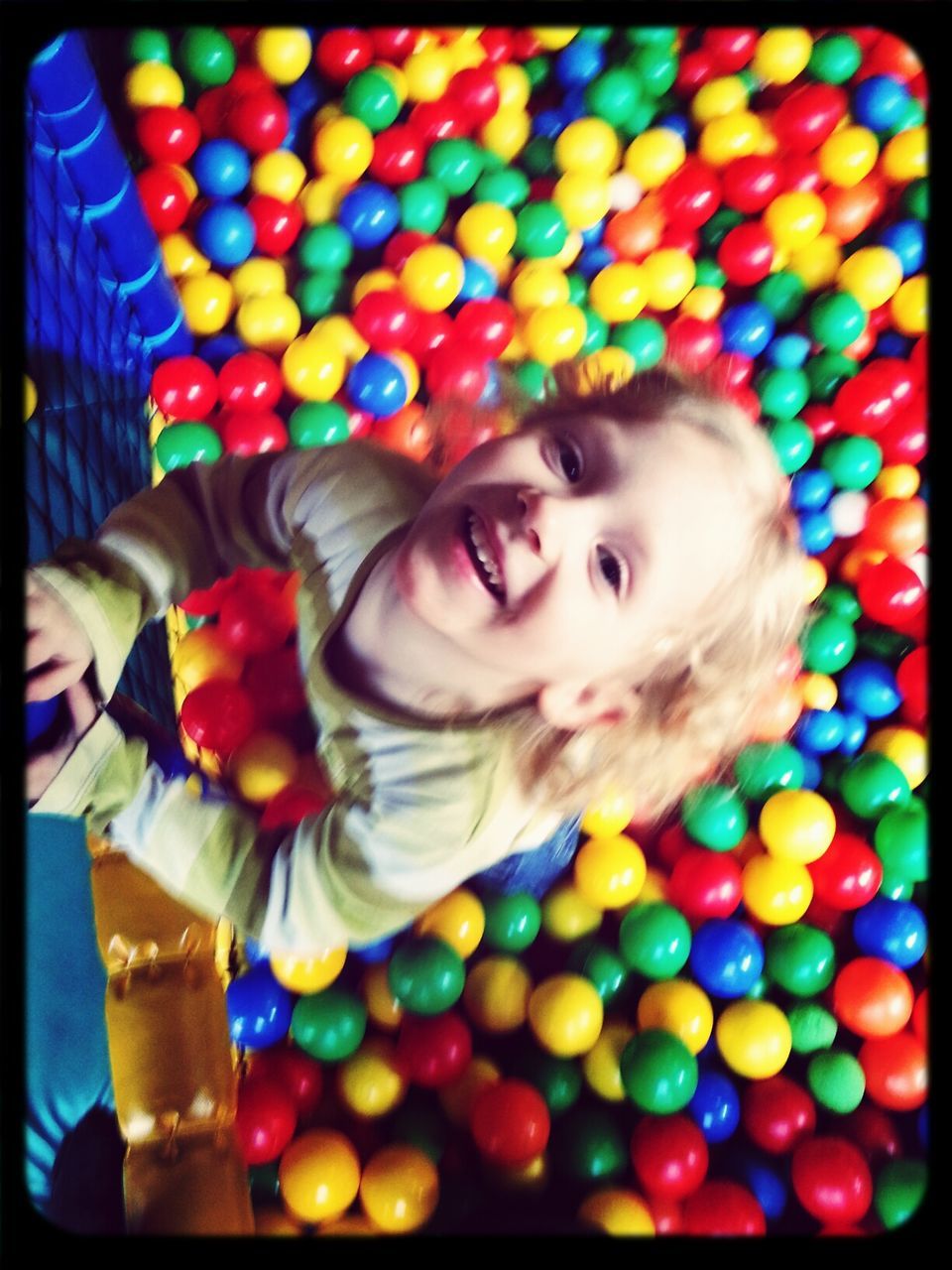 High angle portrait of happy girl standing amidst multi colored balls