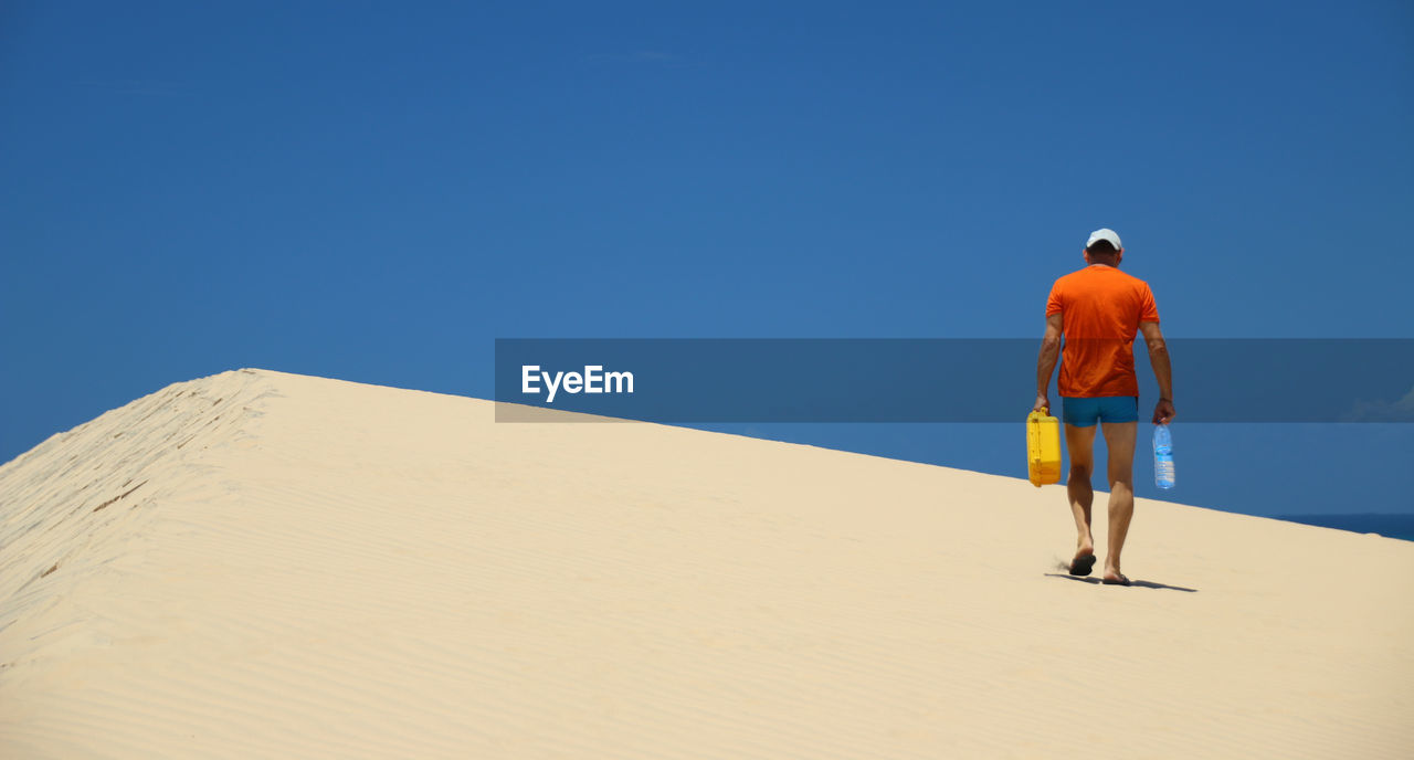 Rear view of man standing on sand dune