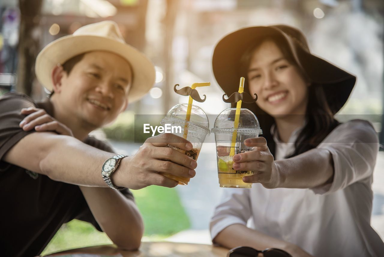 Smiling couple holding juice sitting at restaurant