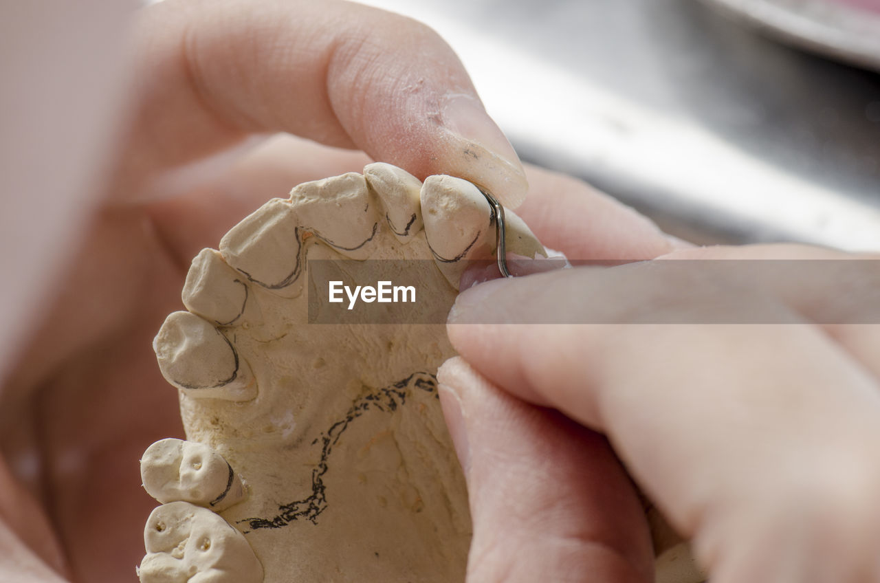 Cropped hands of person working on dentures