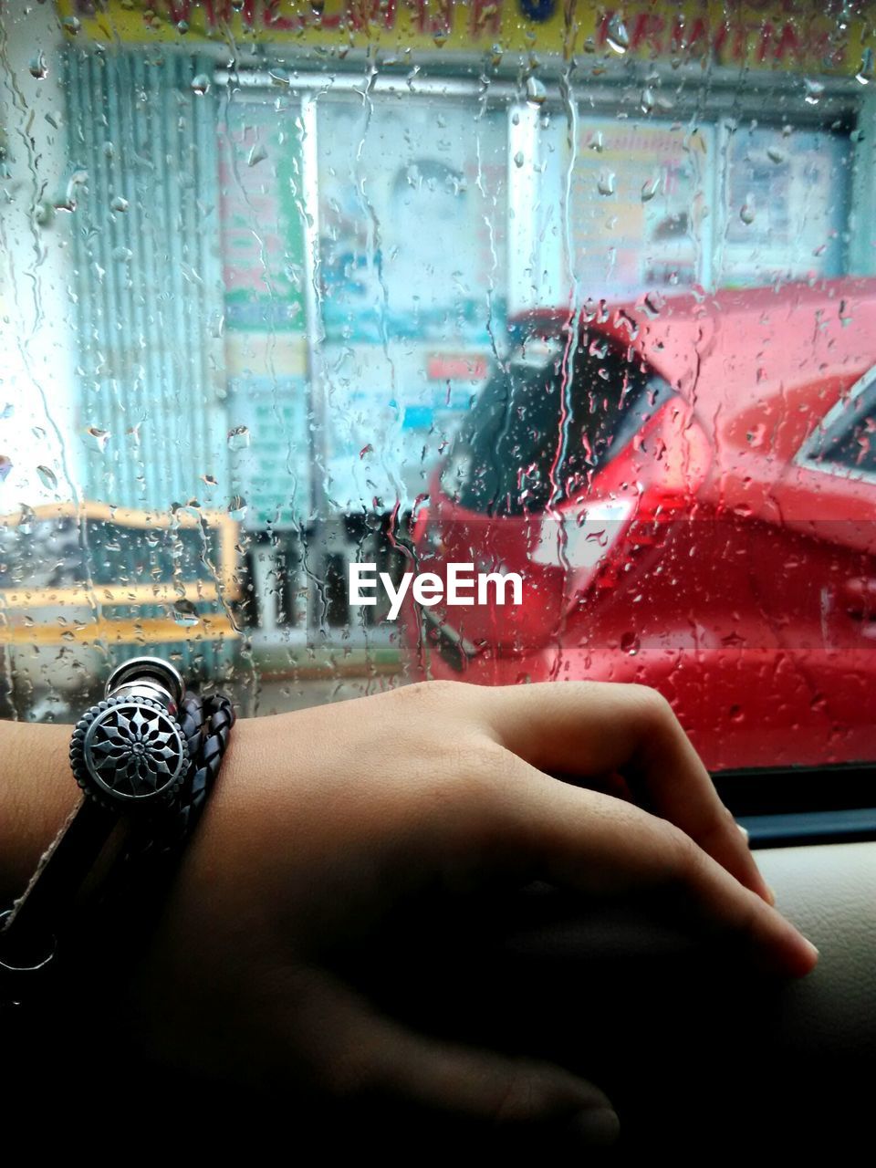 Cropped hand on wet car window during rainy season