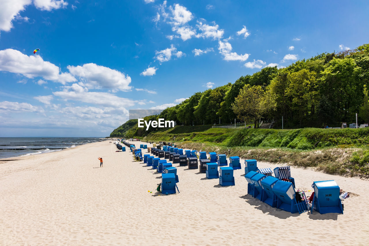 Hooded chairs at beach against blue sky