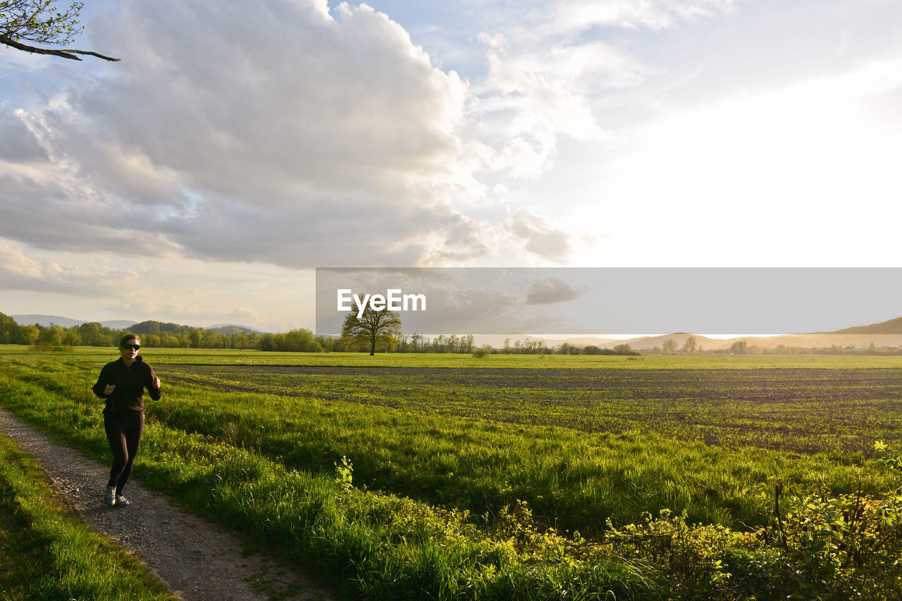 REAR VIEW OF WOMAN WALKING ON FIELD