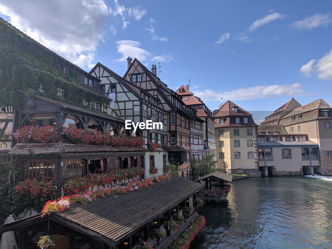 Buildings by river against sky in city