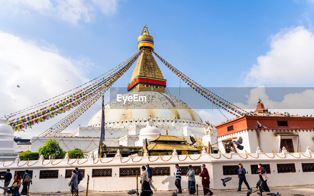 architecture, built structure, travel destinations, religion, travel, temple - building, belief, landmark, sky, building exterior, tourism, temple, spirituality, building, cloud, history, nature, group of people, place of worship, the past, city, tourist, outdoors, large group of people, praying, crowd, tradition, ancient, tower, pagoda, gold, arts culture and entertainment, business finance and industry, walking, adult, men, palace