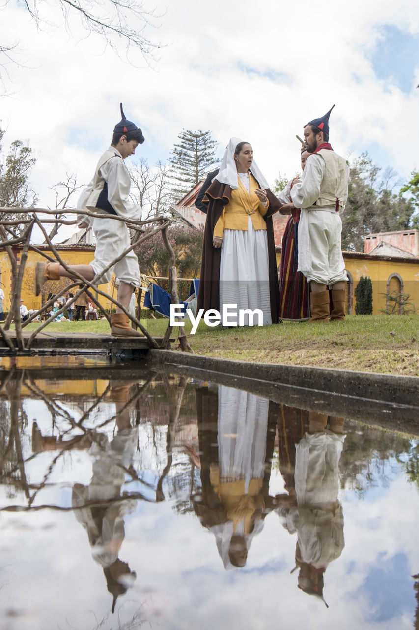 REAR VIEW OF PEOPLE STANDING IN LAKE