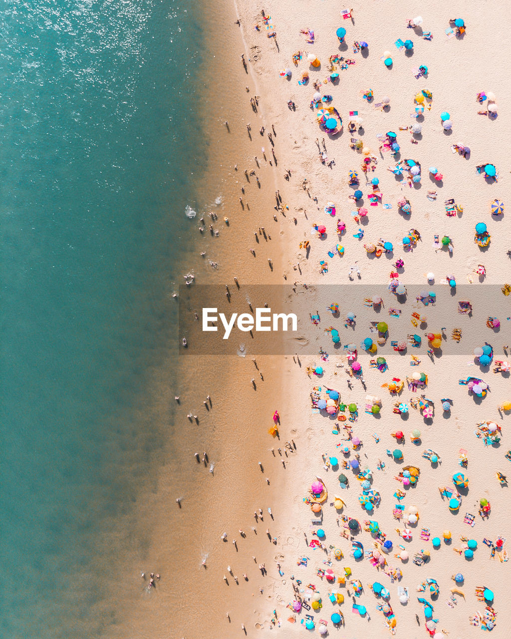 Drone shot of colorful parasols and people at beach during summer