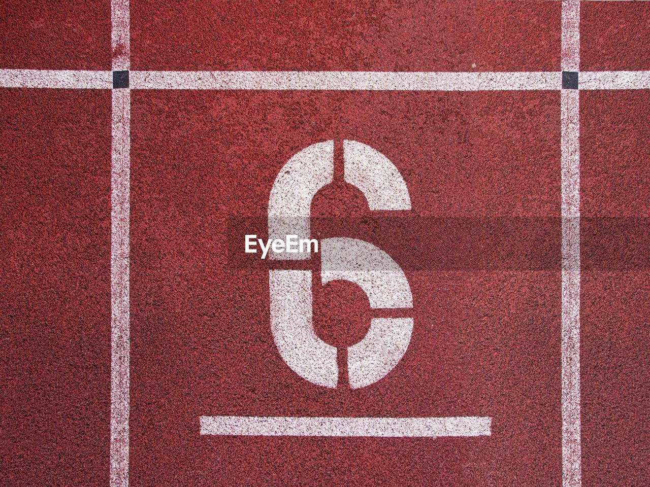 Number six. white athletic track number on red rubber racetrack, texture of racetracks in stadium