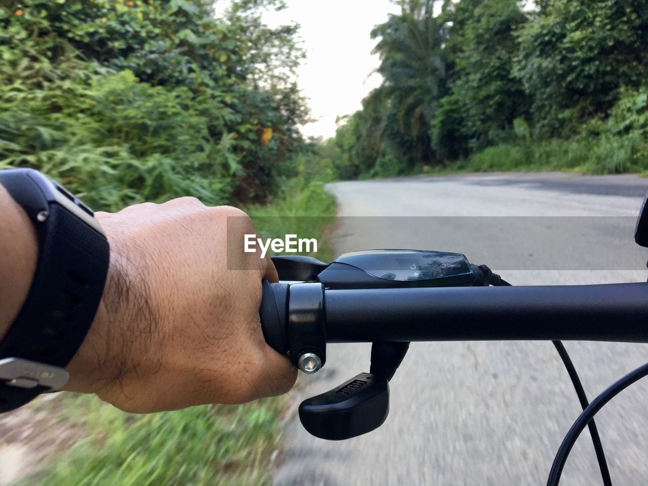 Cropped hand riding bicycle on road