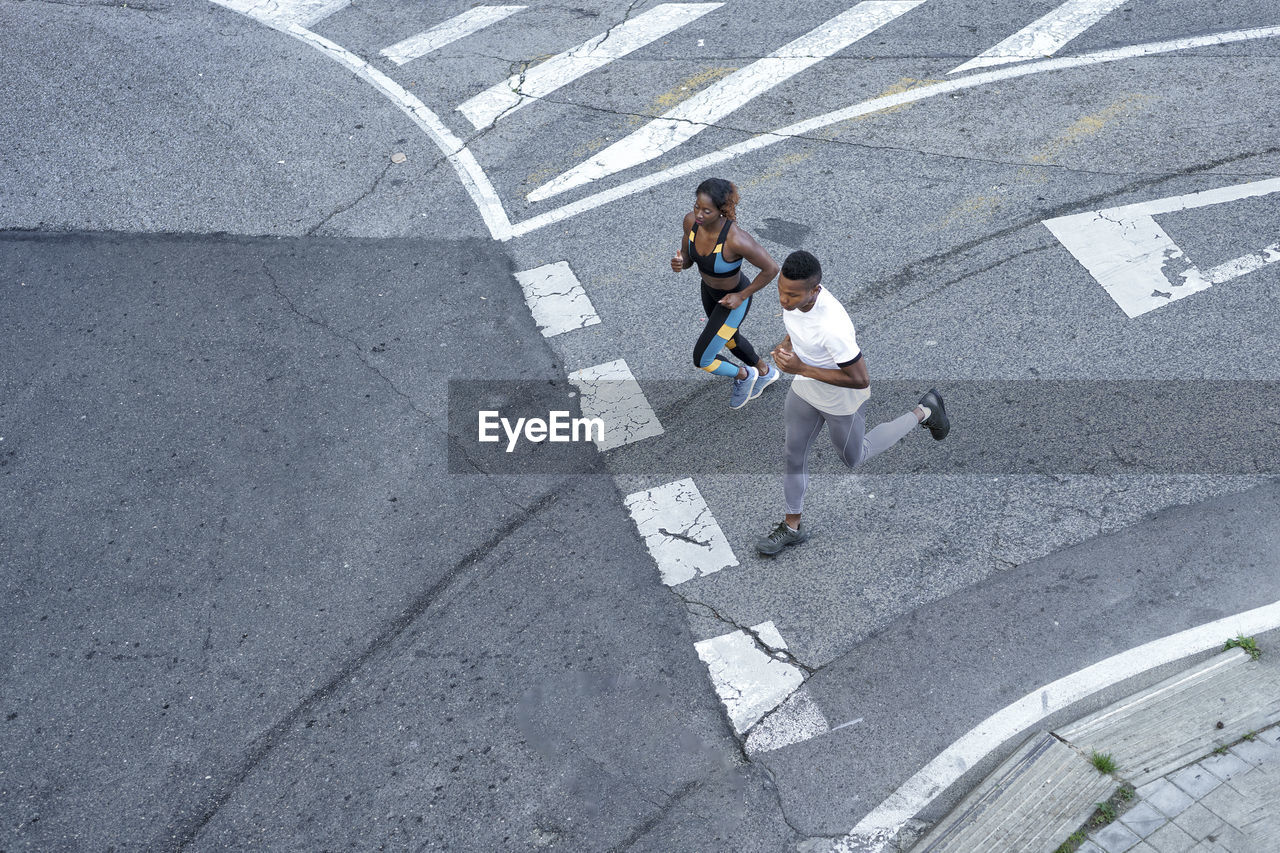 Couple running on road together at city