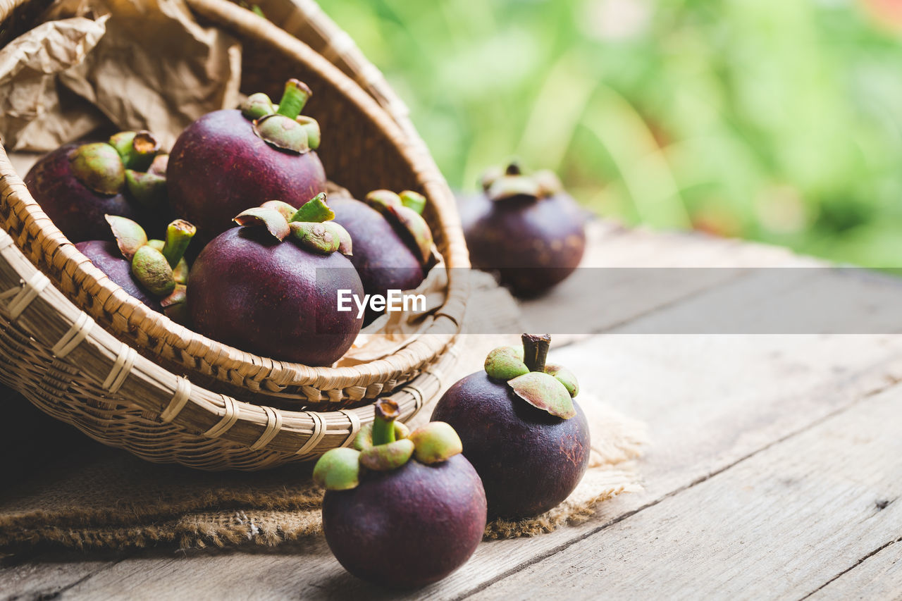 Close-up of purple mangosteens in basket on table