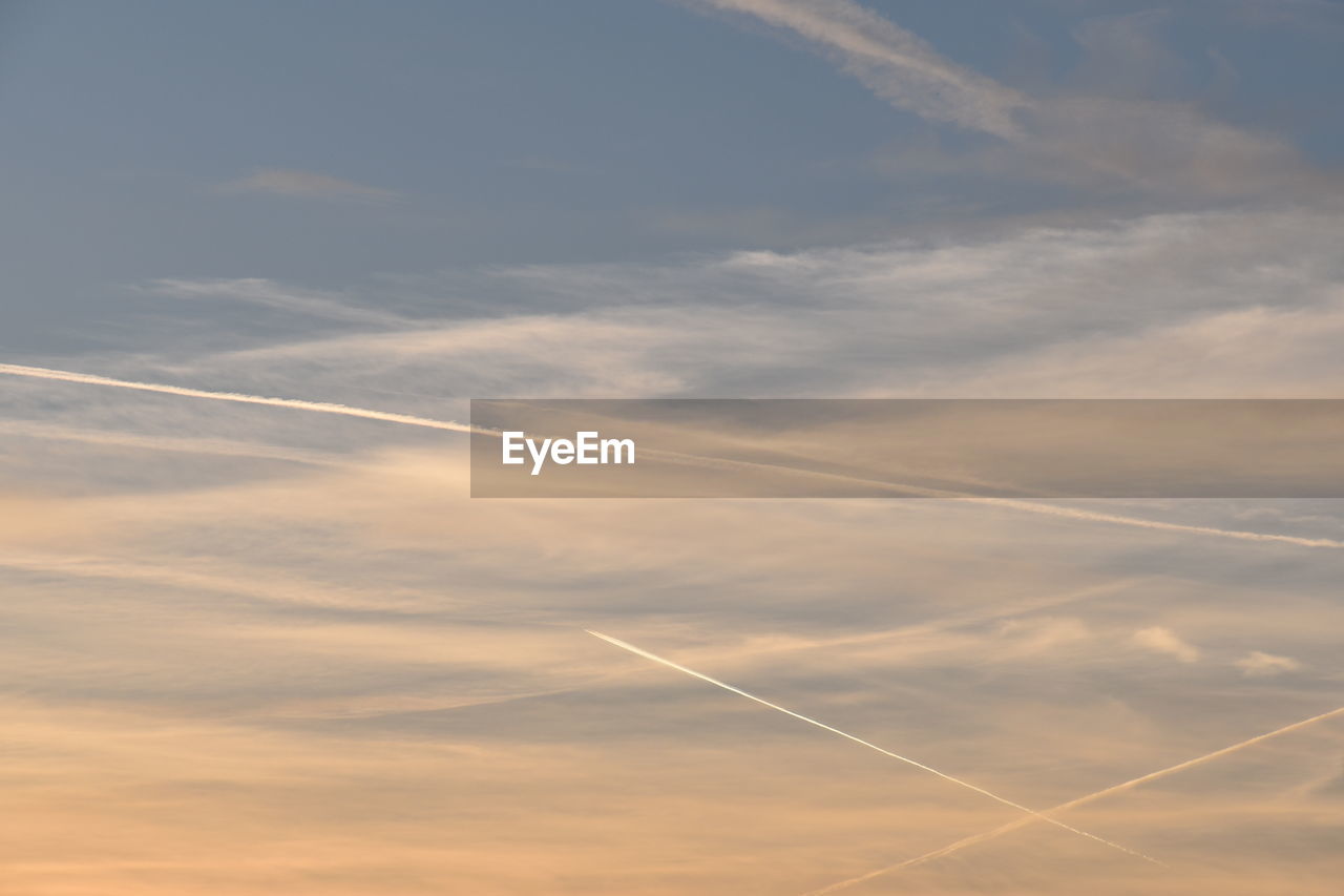 LOW ANGLE VIEW OF VAPOR TRAILS IN SKY DURING SUNSET