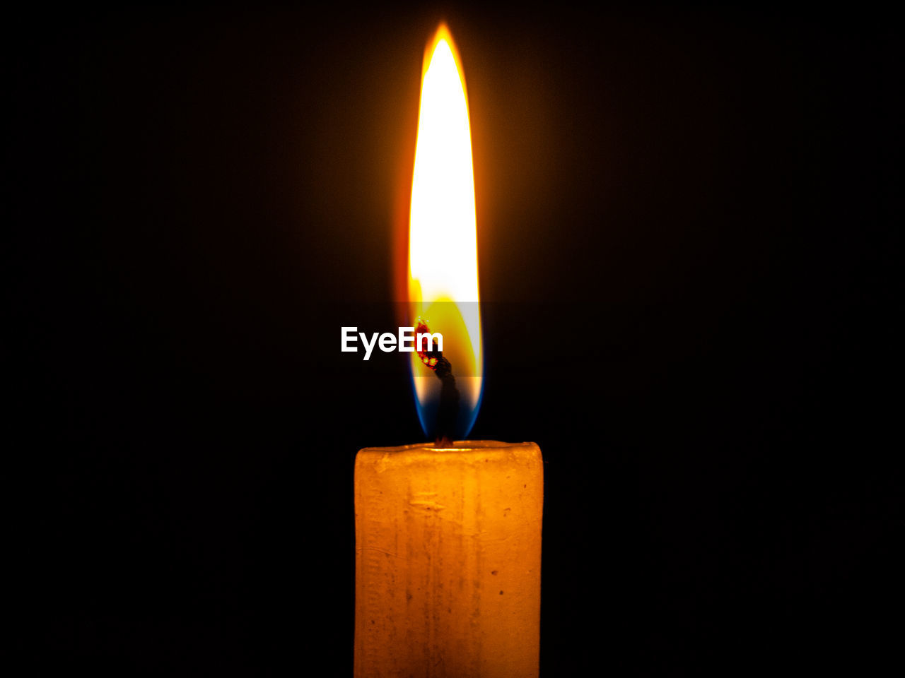 Close-up of burning candle against black background