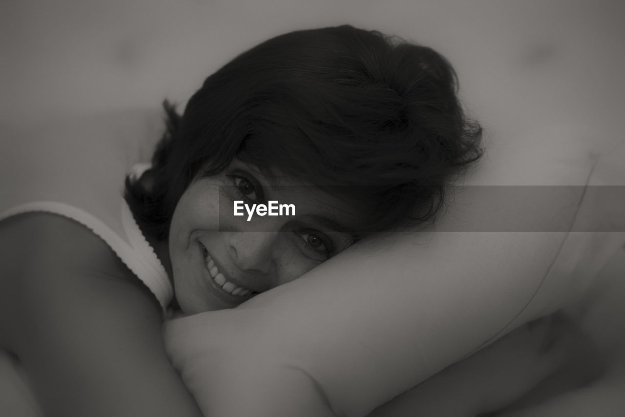 Close-up portrait of woman relaxing on bed at home