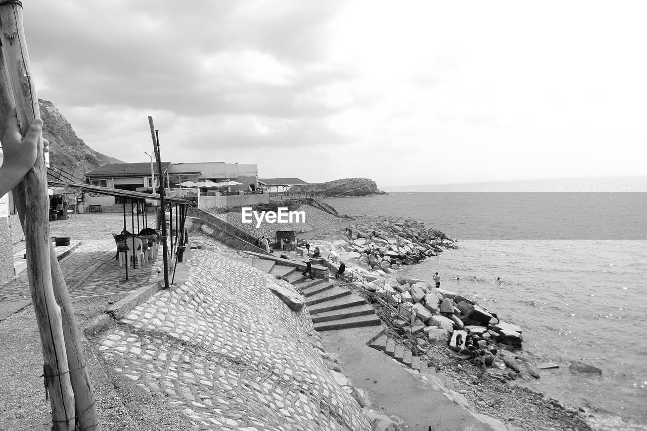 sea, water, sky, beach, black and white, land, nature, monochrome photography, horizon, monochrome, horizon over water, scenics - nature, cloud, beauty in nature, coast, day, tranquility, sand, travel, architecture, tranquil scene, travel destinations, vacation, holiday, trip, transportation, outdoors, tourism, coastline, vehicle, built structure, no people, seascape, nautical vessel, sunlight, wood, pier