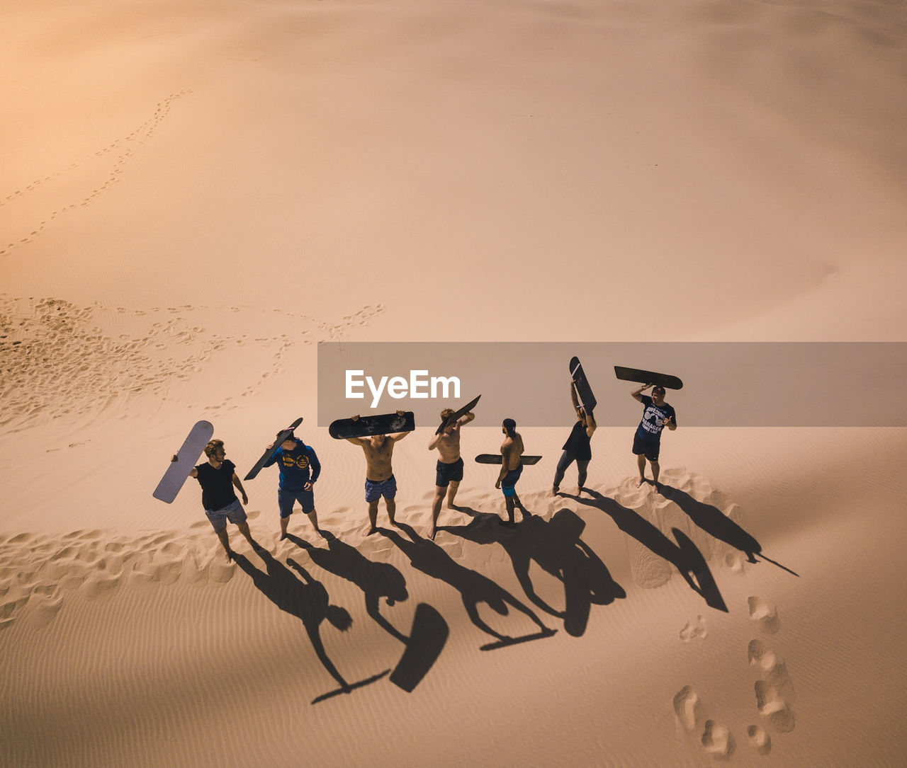 High angle view of male friends carrying surfboard while standing at beach