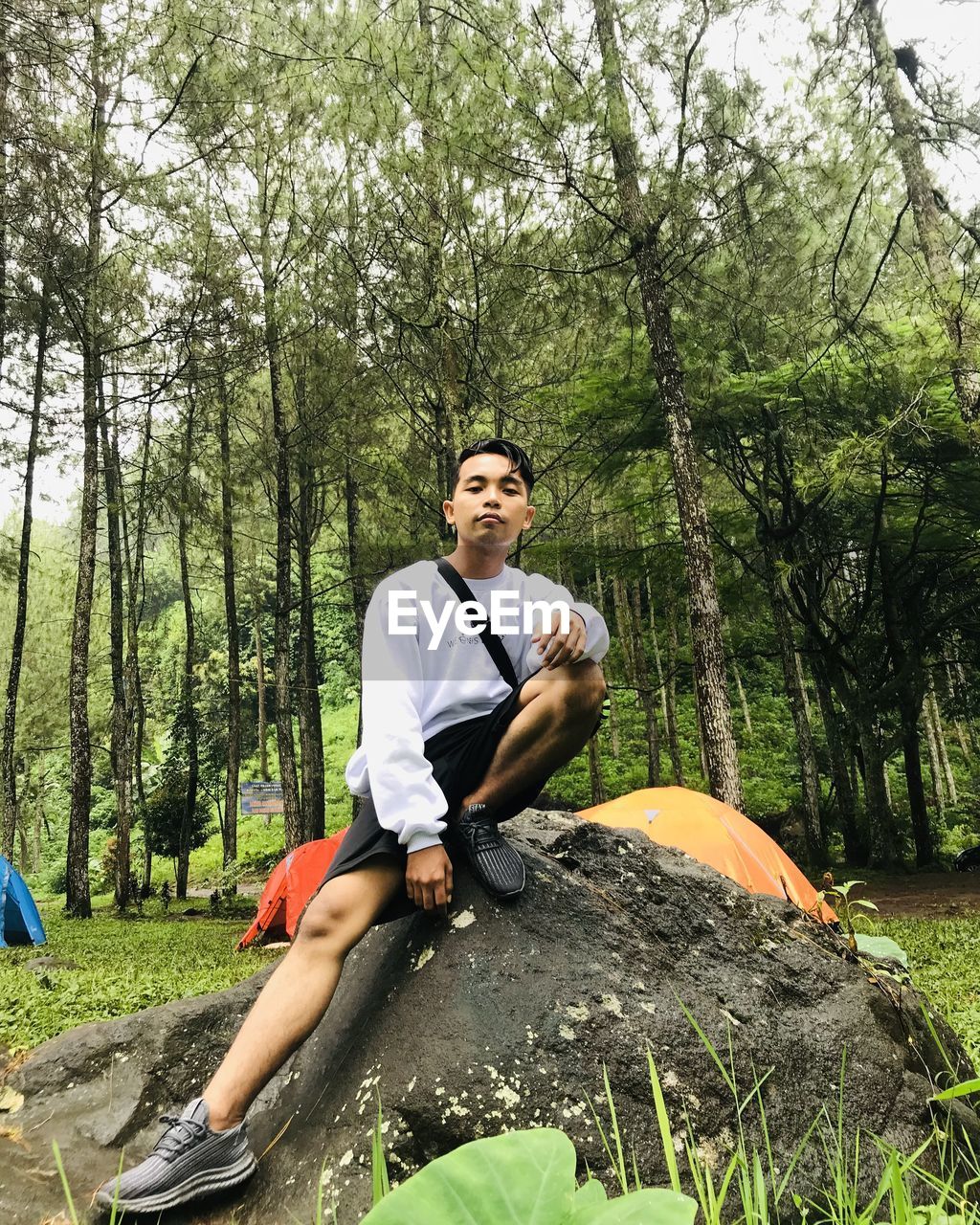 Young man sitting on rock in forest