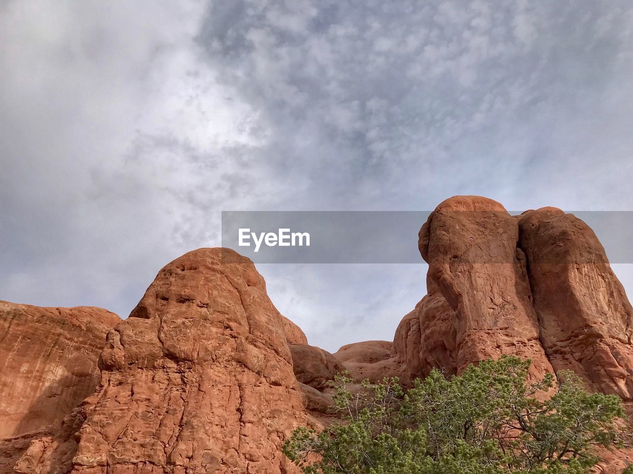 Low angle view of rock formation against cloudy sky