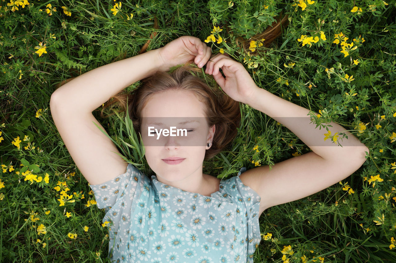 Directly above shot of young woman relaxing on field at park