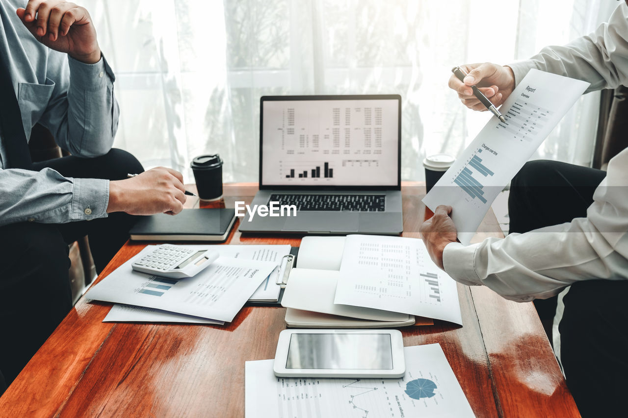 Midsection of business colleagues working at desk in office