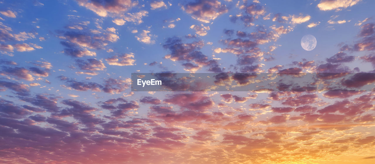 Romantic gradient sky with dramatic clouds and full moon in sunset