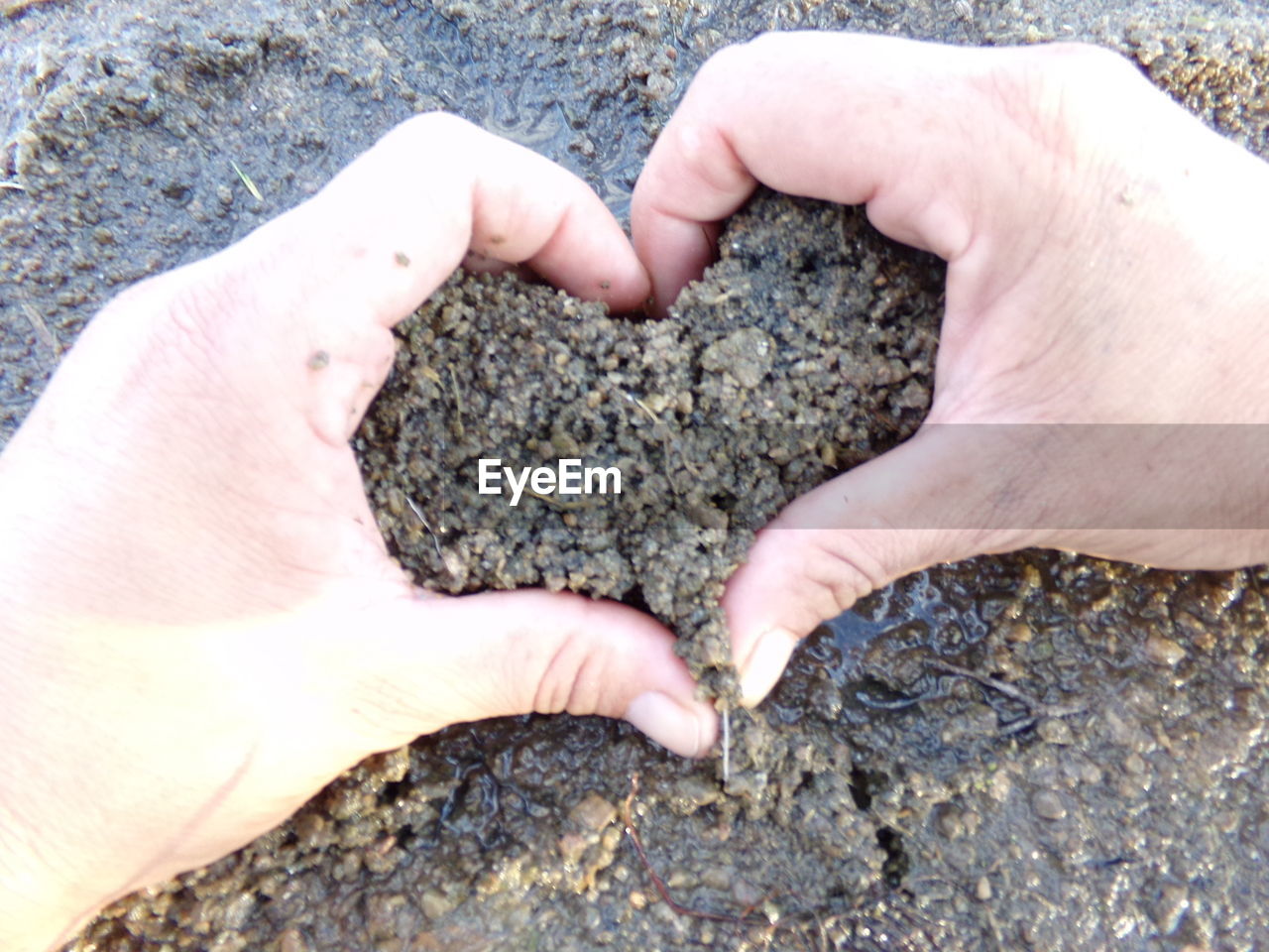 CLOSE-UP OF MAN HAND WITH PEBBLES ON BEACH