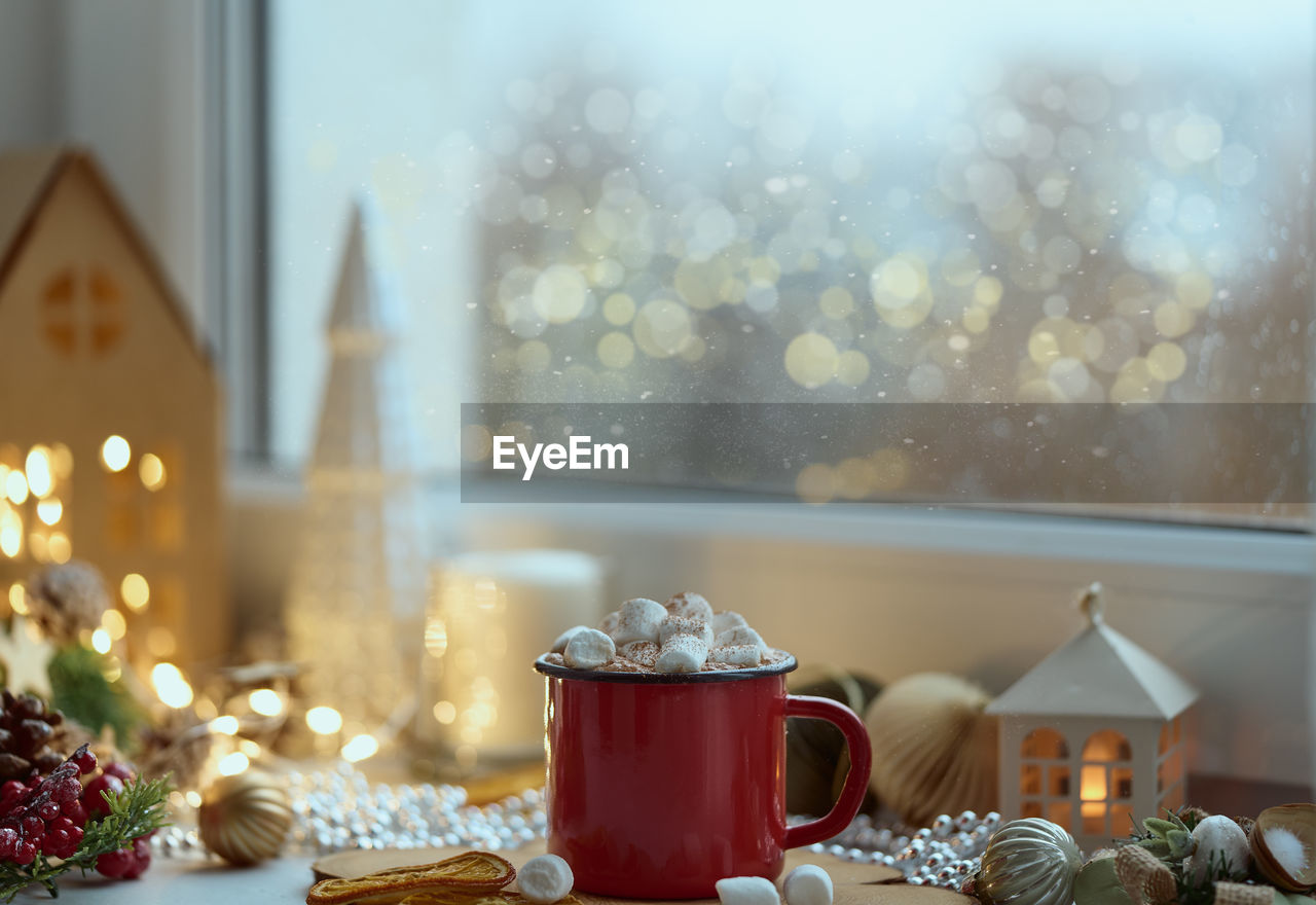 Cozy home christmas atmosphere, window view mug of hot chocolate on windowsill, evening at home