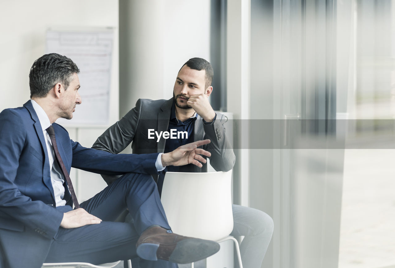 Two businessmen talking in office at the window