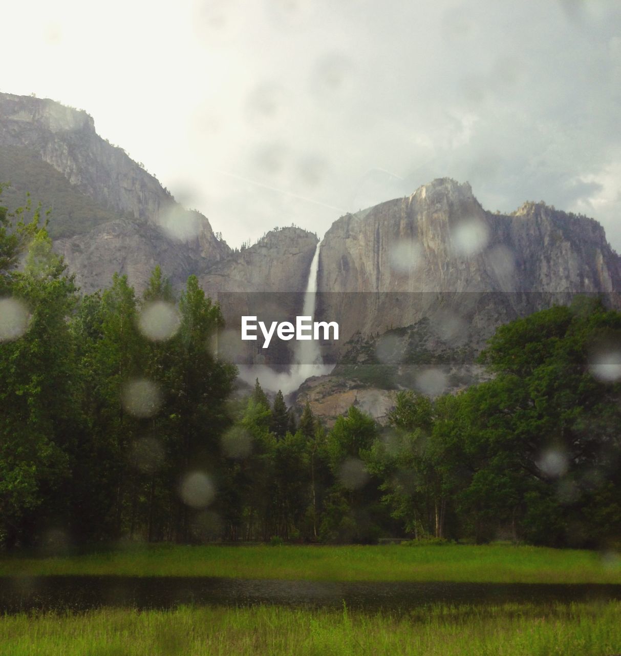 Scenic view of mountains against sky seen through wet glass