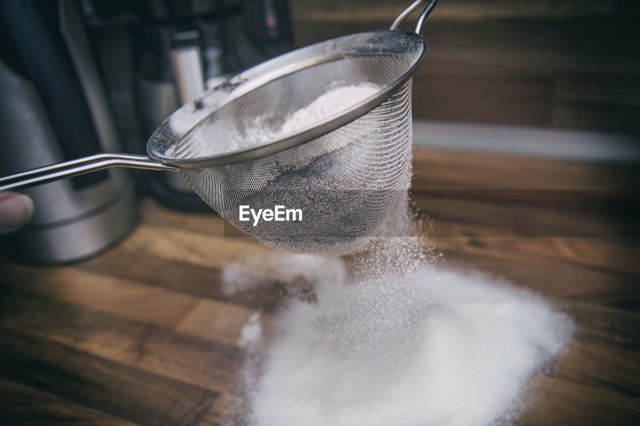 Close-up of colander with sugar in kitchen at table