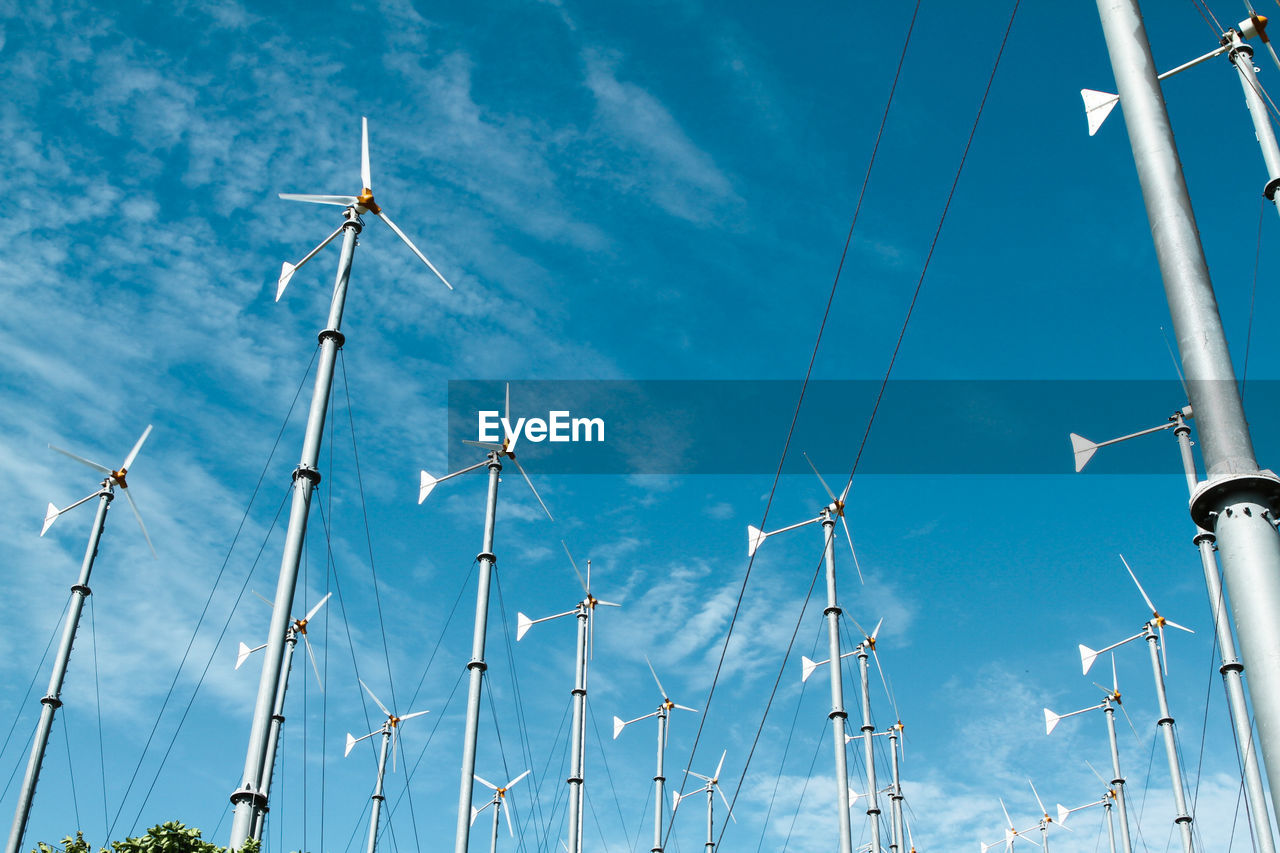 Low angle view of windmills against blue sky