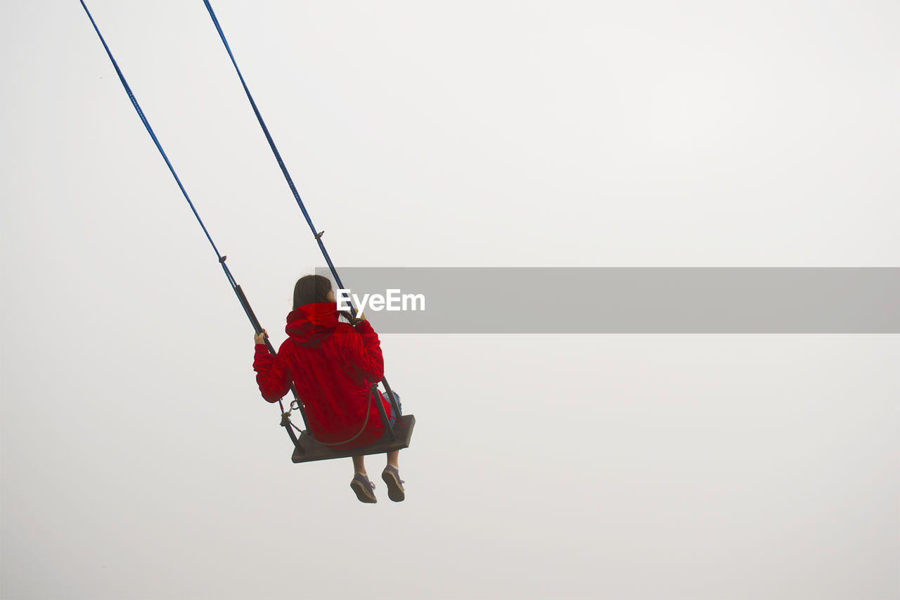 Low angle view of woman swinging against cleat sky